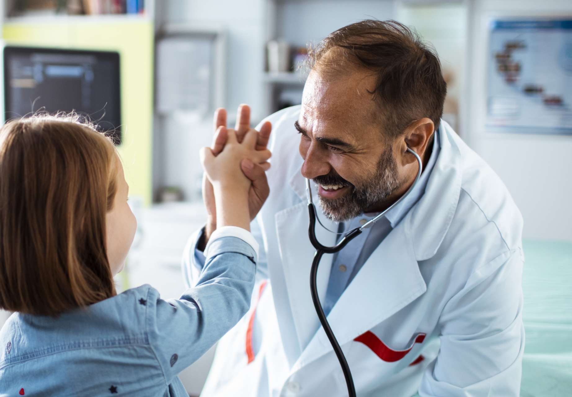 A pediatric orthopedic doctor high fiving a pret-een female patient in his office after discussing her progress using the Thinks Works brace for Adolescent Idiopathic Scoliosis (AIS)